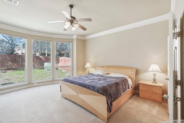 bedroom featuring ceiling fan, crown molding, light carpet, and multiple windows