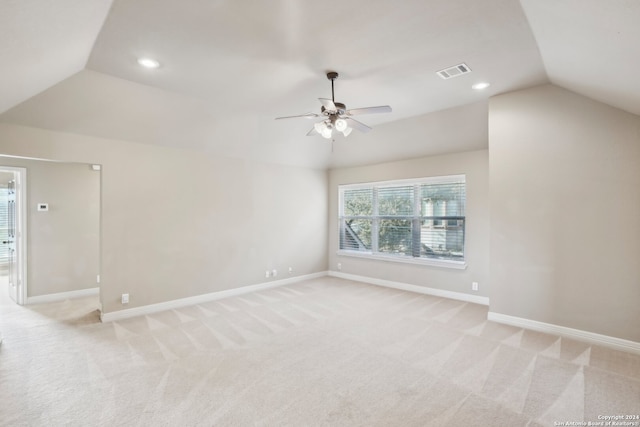 empty room with light colored carpet, vaulted ceiling, and ceiling fan