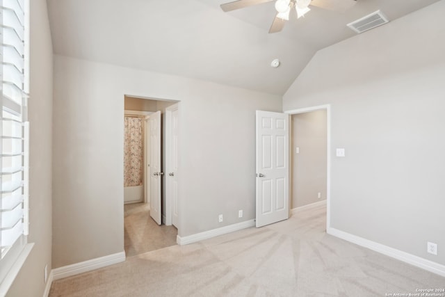 carpeted empty room featuring lofted ceiling, ceiling fan, and a healthy amount of sunlight