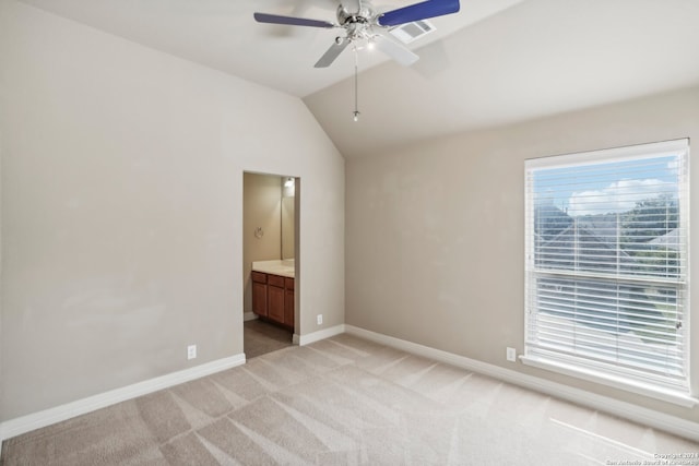 unfurnished bedroom with ceiling fan, vaulted ceiling, light carpet, and ensuite bath