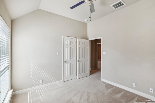 unfurnished bedroom featuring a closet, light colored carpet, vaulted ceiling, and ceiling fan