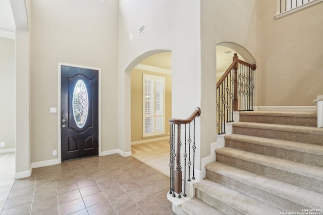 tiled foyer entrance with crown molding and a high ceiling