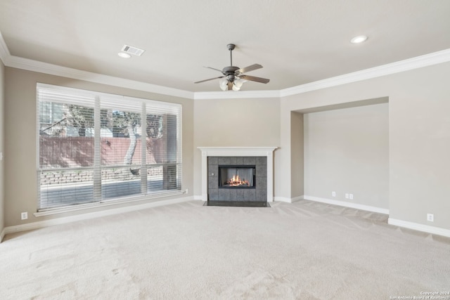 unfurnished living room featuring a tile fireplace, crown molding, ceiling fan, and light colored carpet