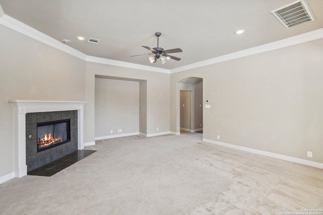 unfurnished living room with light carpet, a tile fireplace, crown molding, and ceiling fan