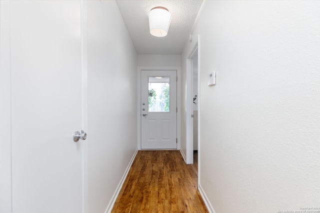 doorway with a textured ceiling and hardwood / wood-style flooring