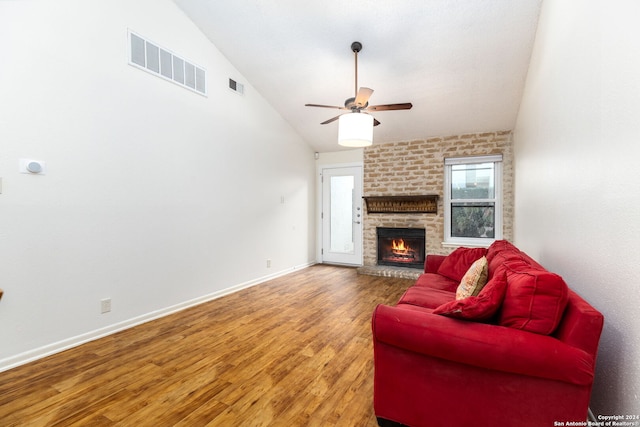 living room featuring hardwood / wood-style flooring, ceiling fan, a brick fireplace, and vaulted ceiling