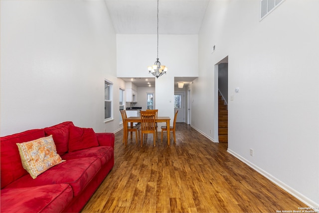 living room with hardwood / wood-style flooring, a notable chandelier, and a towering ceiling