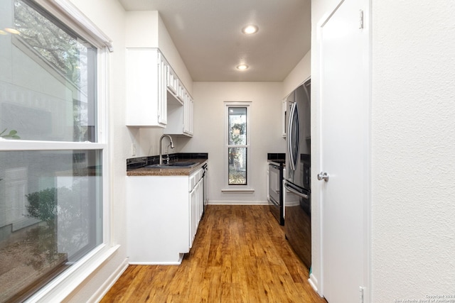 kitchen with white cabinets, stainless steel fridge, light wood-type flooring, and sink