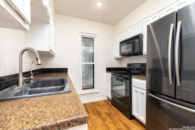 kitchen featuring sink, white cabinets, black appliances, and light hardwood / wood-style floors