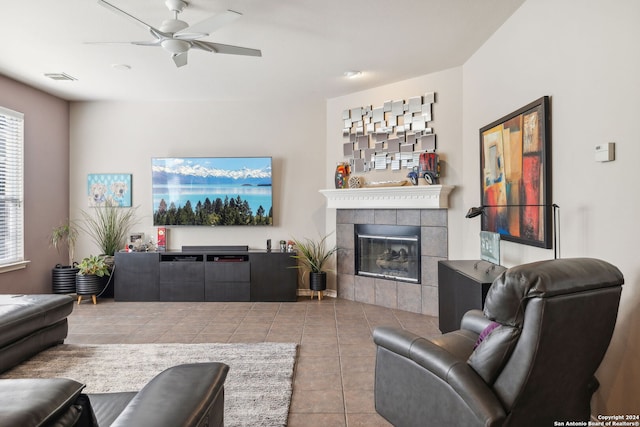 living room with a tiled fireplace, ceiling fan, and light tile patterned flooring