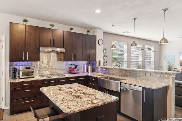 kitchen featuring stainless steel appliances, backsplash, kitchen peninsula, decorative light fixtures, and a breakfast bar area