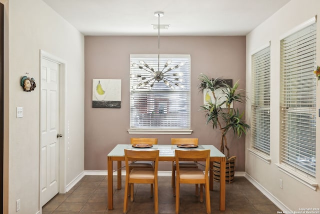 dining room with dark tile patterned flooring and a notable chandelier