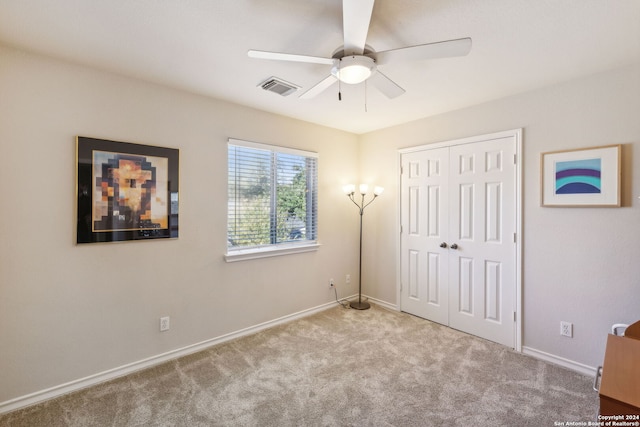 unfurnished bedroom with ceiling fan, a closet, and light carpet