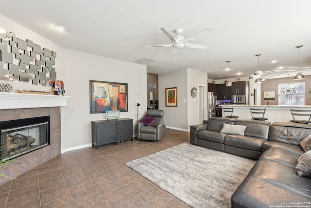 living room featuring a fireplace, dark tile patterned flooring, and ceiling fan