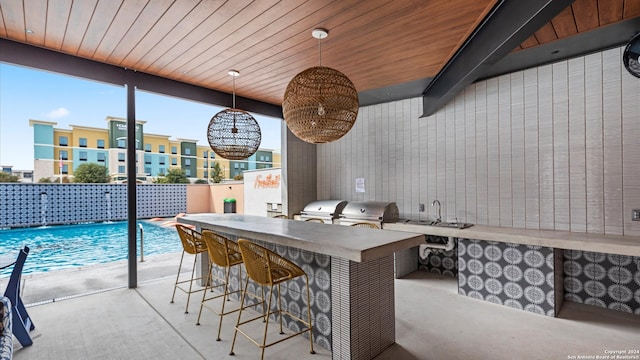 interior space featuring area for grilling, pool water feature, an outdoor kitchen, and a wet bar