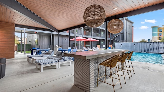 view of patio featuring pool water feature, a bar, and a community pool