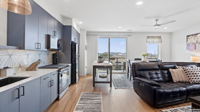 kitchen with decorative backsplash, ceiling fan, light wood-type flooring, and stainless steel appliances