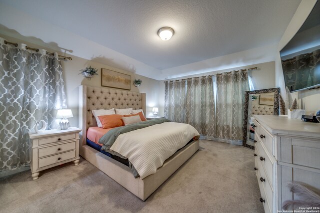 bedroom featuring light colored carpet and a textured ceiling