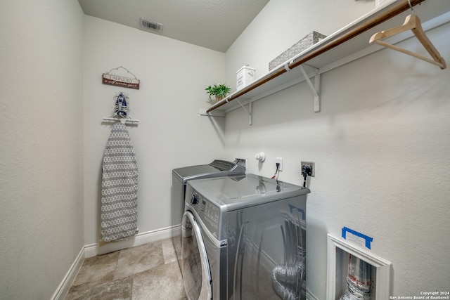 washroom with washer and clothes dryer and a textured ceiling