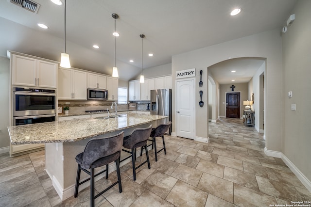 kitchen with white cabinets, appliances with stainless steel finishes, a center island with sink, and sink