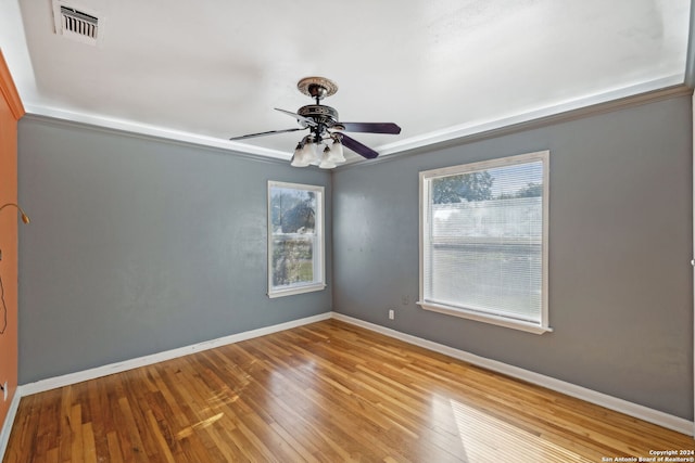 empty room featuring ceiling fan, wood-type flooring, ornamental molding, and a wealth of natural light