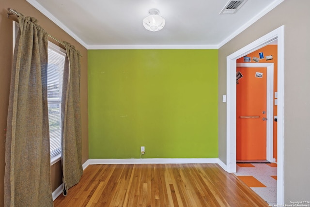 empty room featuring wood-type flooring and crown molding