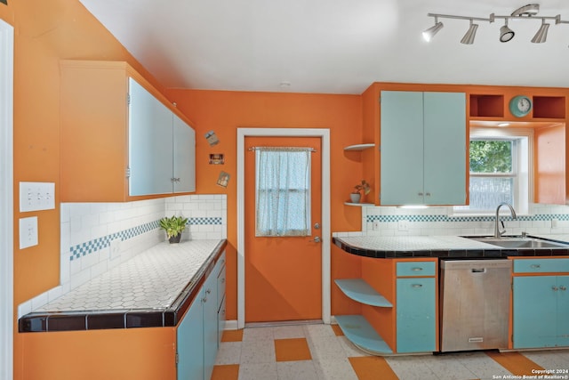 kitchen with backsplash, tile counters, dishwasher, and sink