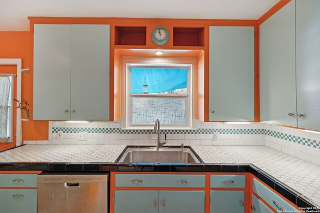 kitchen featuring stainless steel dishwasher, a healthy amount of sunlight, sink, and tile countertops