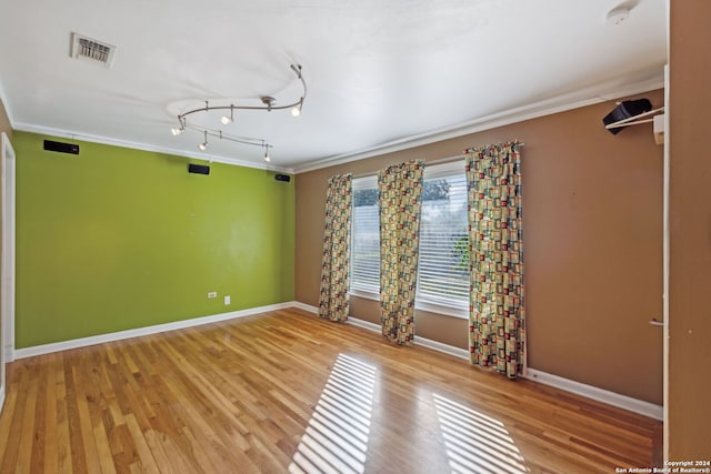 empty room featuring crown molding, light hardwood / wood-style flooring, and track lighting