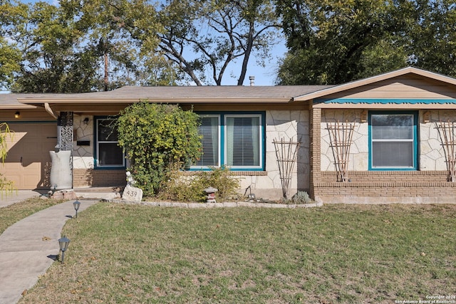 ranch-style home featuring a garage and a front lawn