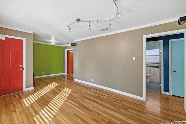 spare room featuring crown molding, light hardwood / wood-style flooring, and rail lighting