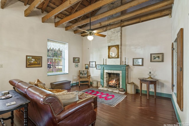 living room featuring dark hardwood / wood-style floors, ceiling fan, a towering ceiling, beam ceiling, and a large fireplace