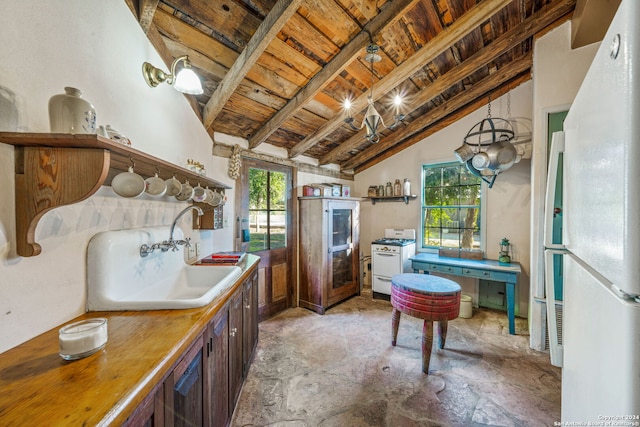 kitchen featuring white appliances, sink, pendant lighting, lofted ceiling with beams, and a chandelier