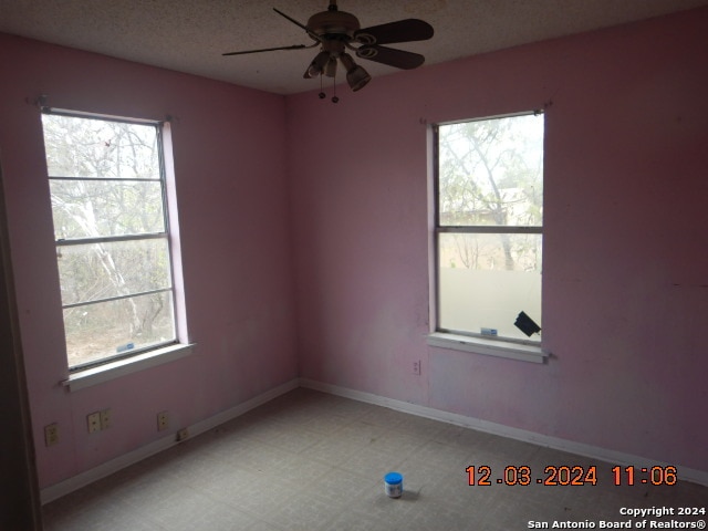 empty room with ceiling fan, a healthy amount of sunlight, and a textured ceiling