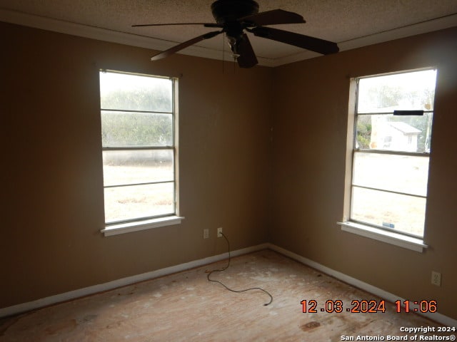 spare room with ceiling fan, a textured ceiling, and a wealth of natural light