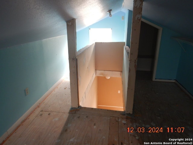 additional living space with a textured ceiling and vaulted ceiling