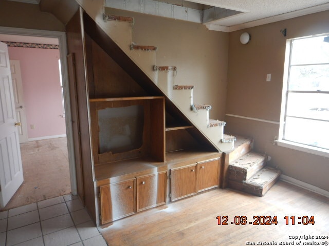 staircase featuring a textured ceiling, tile patterned floors, a wealth of natural light, and ornamental molding