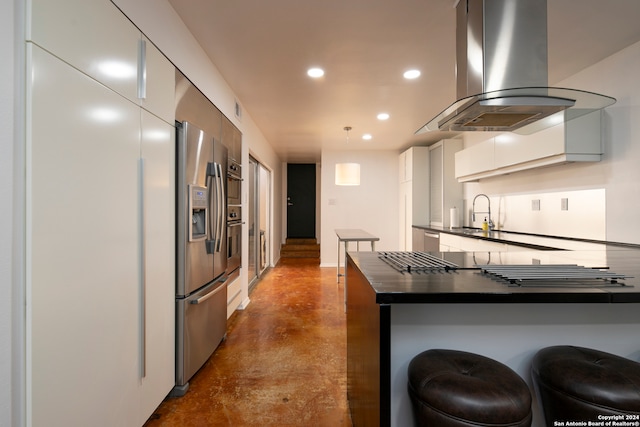 kitchen with kitchen peninsula, island exhaust hood, decorative light fixtures, a breakfast bar, and appliances with stainless steel finishes