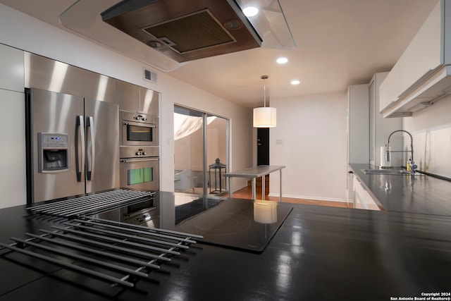 kitchen featuring sink, white cabinets, stainless steel appliances, and decorative light fixtures