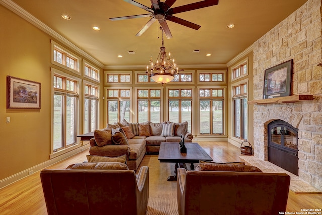 living room with ceiling fan with notable chandelier, light hardwood / wood-style floors, ornamental molding, and a fireplace