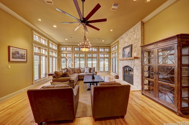 living room with a stone fireplace, light hardwood / wood-style flooring, ceiling fan with notable chandelier, and ornamental molding