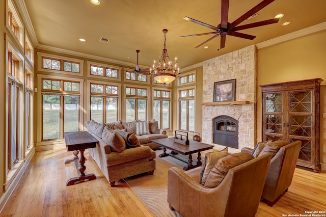 living room featuring crown molding, a towering ceiling, light hardwood / wood-style floors, a fireplace, and ceiling fan with notable chandelier