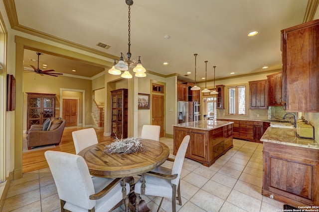 dining area featuring sink, light tile patterned floors, ceiling fan with notable chandelier, and ornamental molding