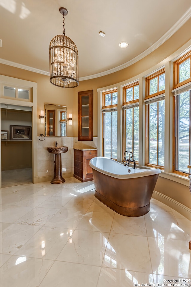 bathroom featuring a tub to relax in, ornamental molding, and a notable chandelier