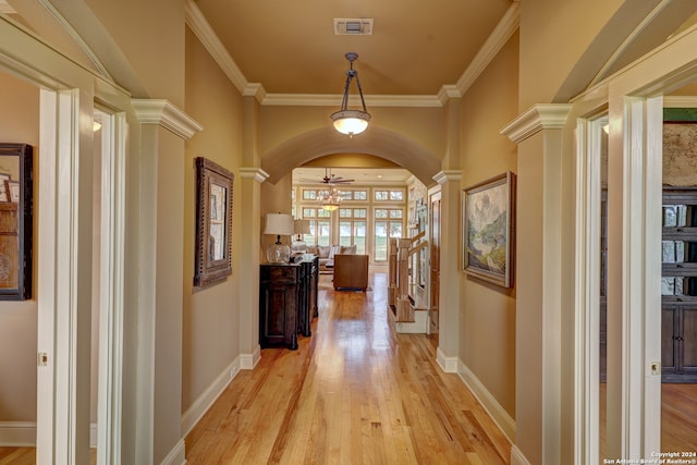 corridor featuring light wood-type flooring, ornate columns, and ornamental molding