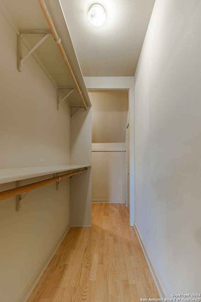 walk in closet with light hardwood / wood-style floors