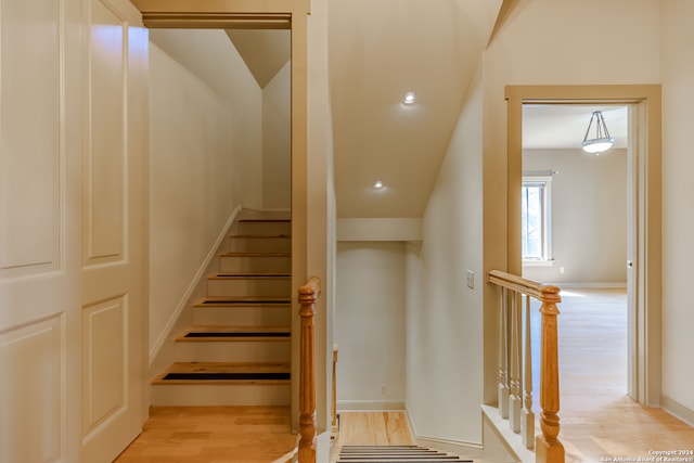 stairway featuring hardwood / wood-style floors and vaulted ceiling