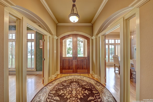 foyer entrance featuring french doors, ornamental molding, and light wood-type flooring