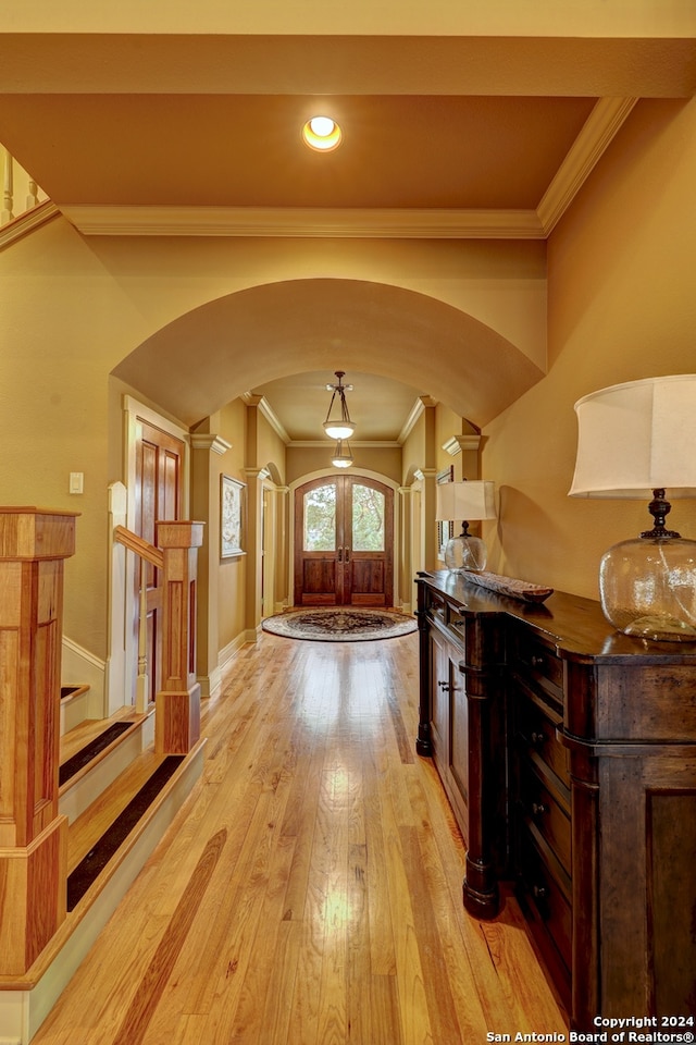 hallway featuring ornate columns, light hardwood / wood-style flooring, french doors, and ornamental molding