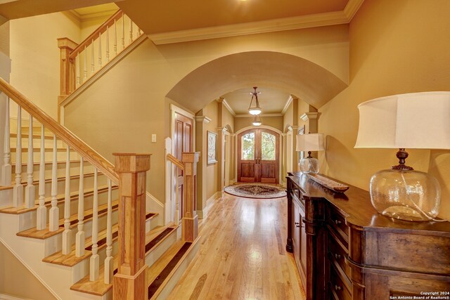 entrance foyer featuring light wood-type flooring, ornamental molding, and french doors